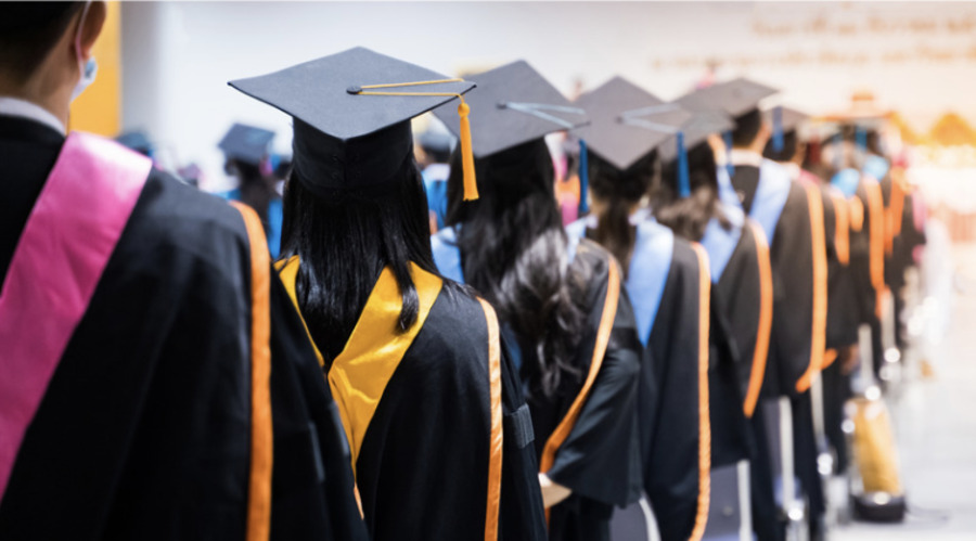 A picture of students standing in line with their graduation caps and gowns. 