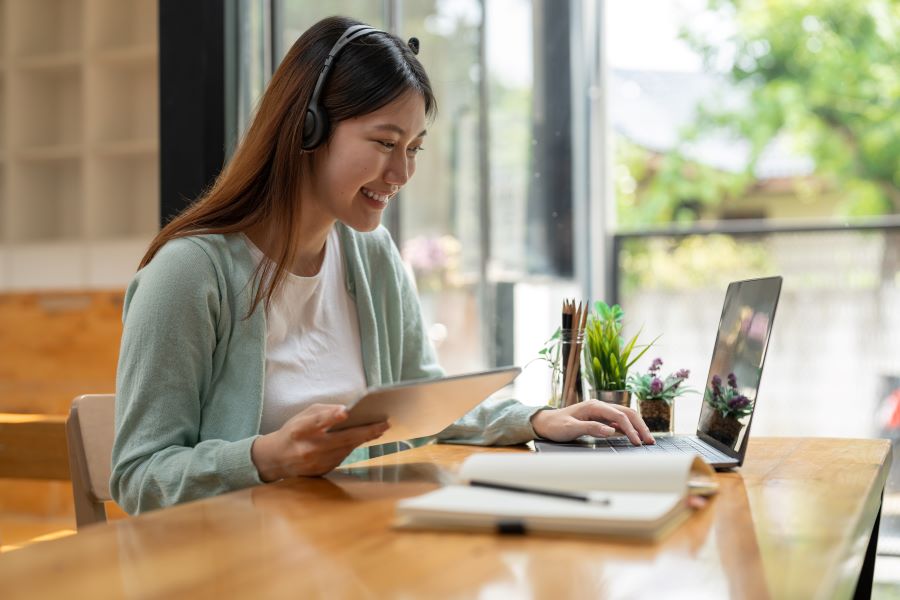 Woman taking notes while learning online. 