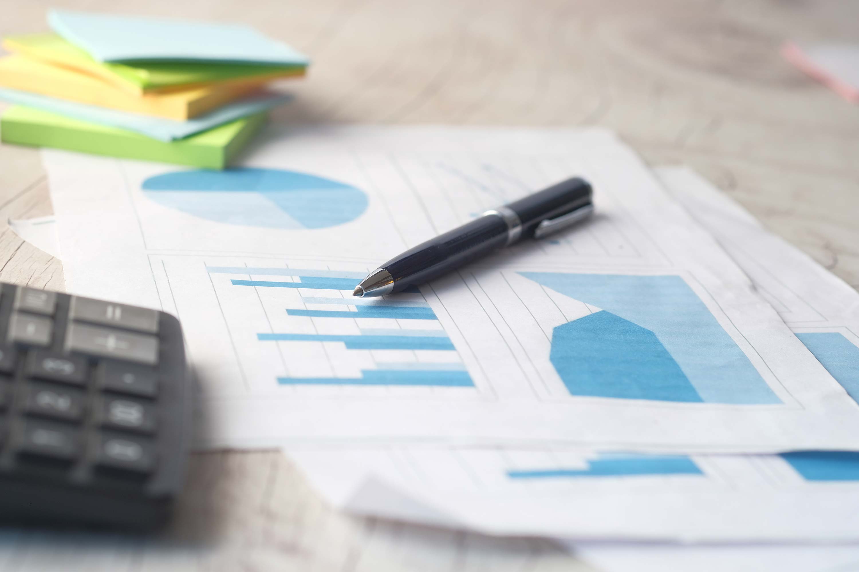 financial graph, calculator and notepad on table.